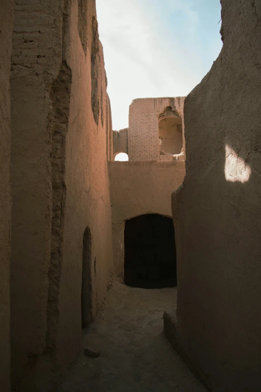 a narrow alley with old adobe buildings and one door open