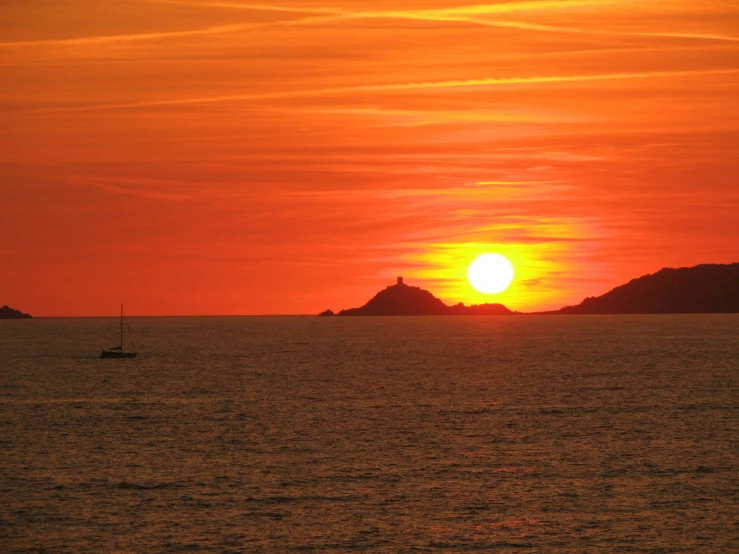 the sun rises over the water and a boat in front