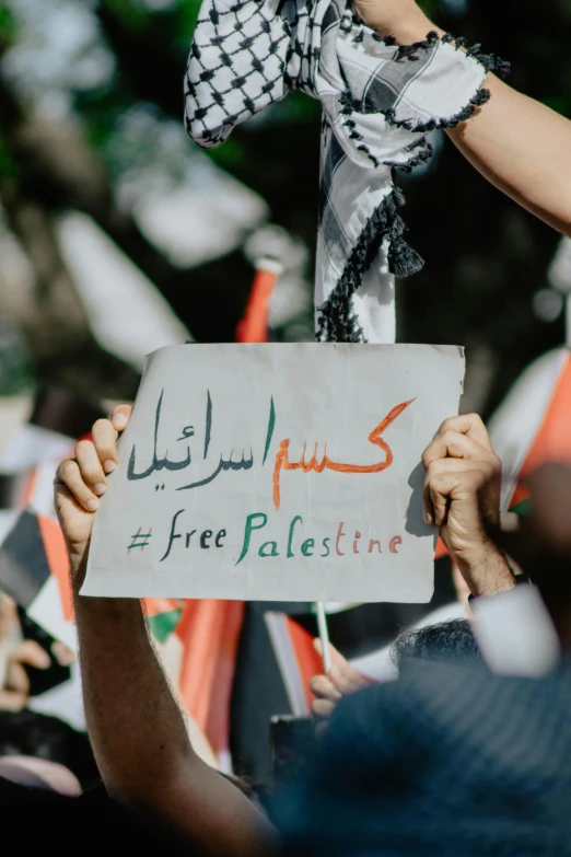 a protest with many hands holding signs and flags