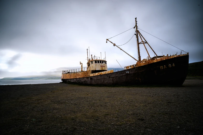 a very old boat on a beach with a cloudy sky