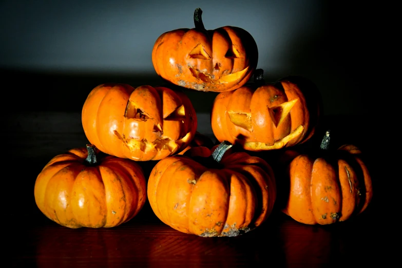 five orange carved pumpkins sitting on top of each other