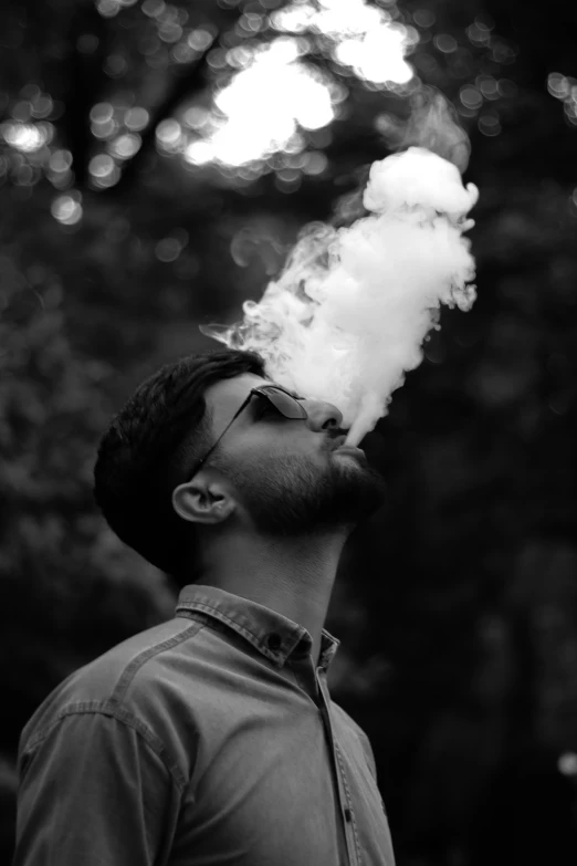 a man in glasses blowing a wick of smoke into the air