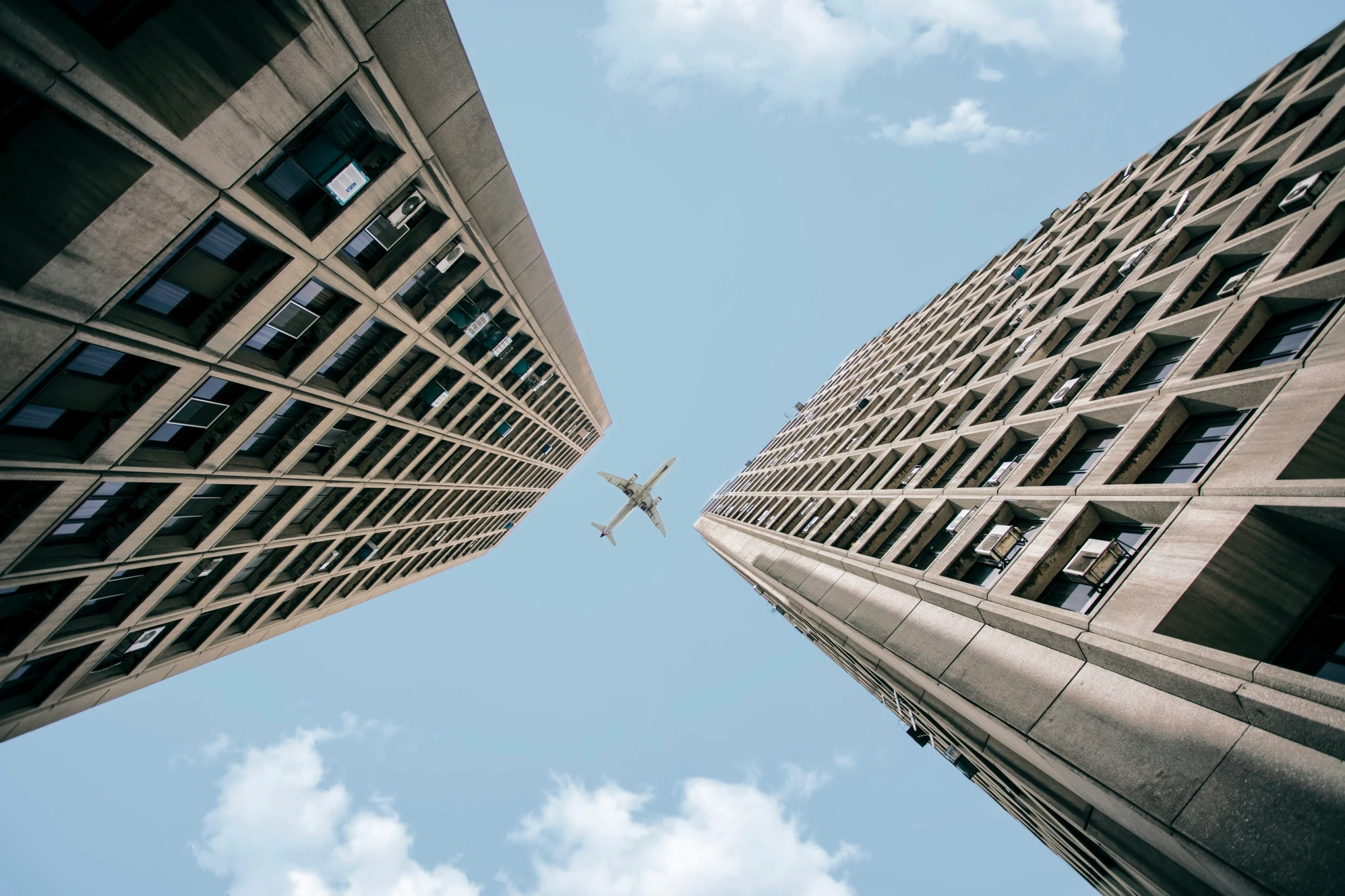 an airplane flying by in the middle of some buildings