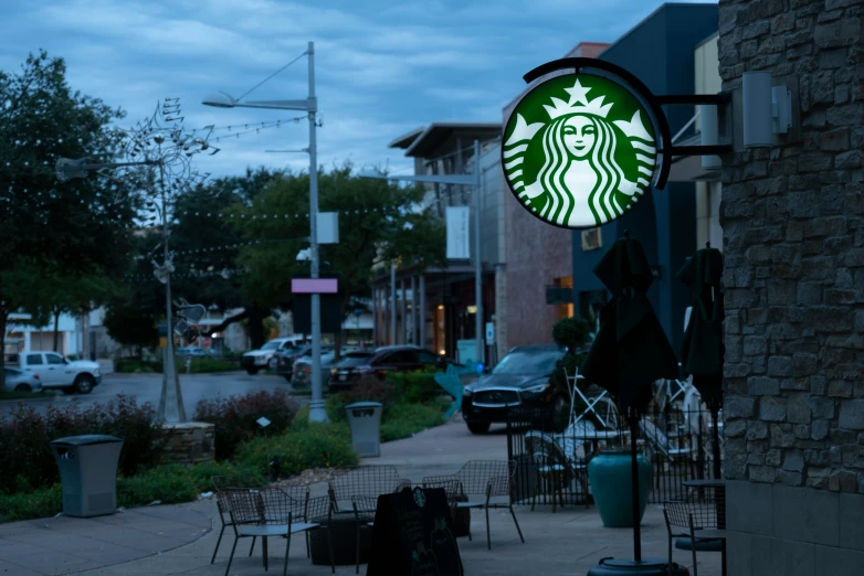 a starbucks sign and street side cafe at dusk