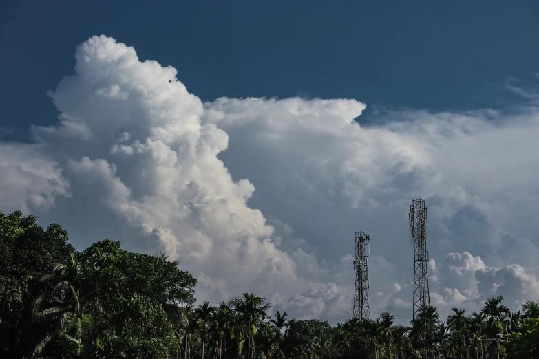 a clock tower and several cellular towers in front of a cloudy sky