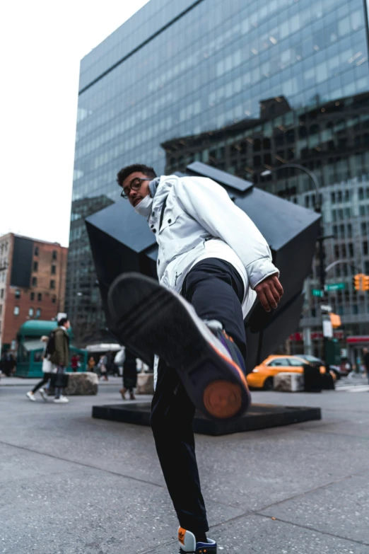 a young man kicking a skateboard outside a large building