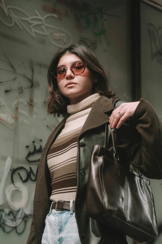 a woman with sunglasses stands near some graffiti