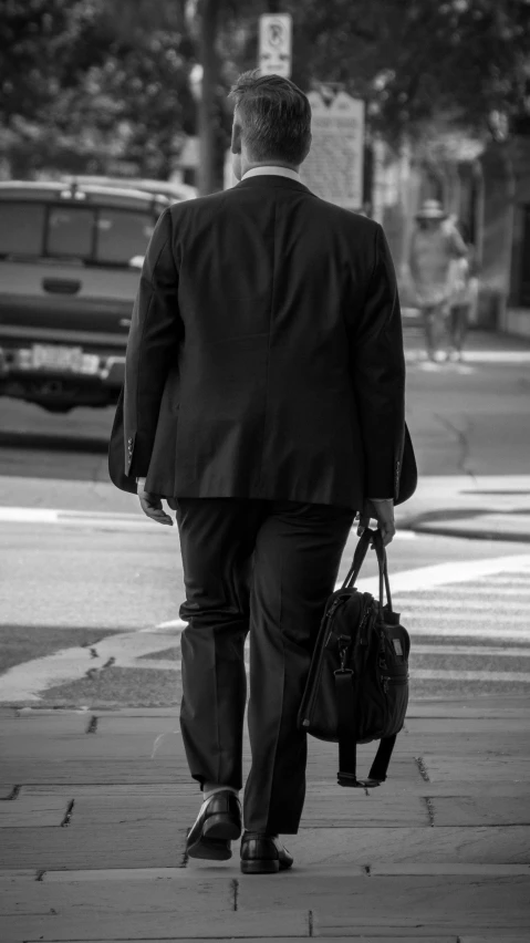 man walking down street with luggage at it's side
