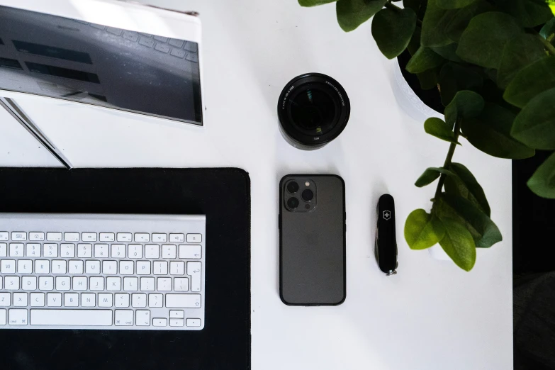 a desk that has a laptop, monitor, cellphone and a flower