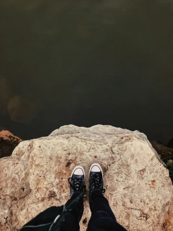 someone is standing on a rock overlooking a large body of water