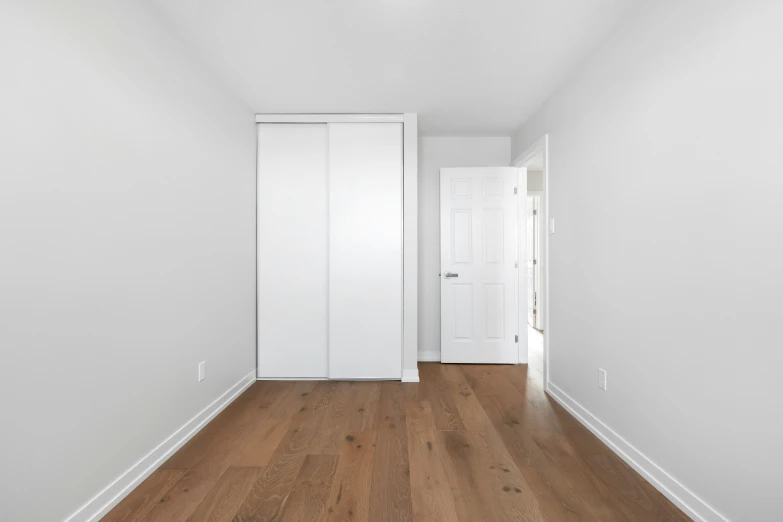 an empty room with white doors and wooden floors