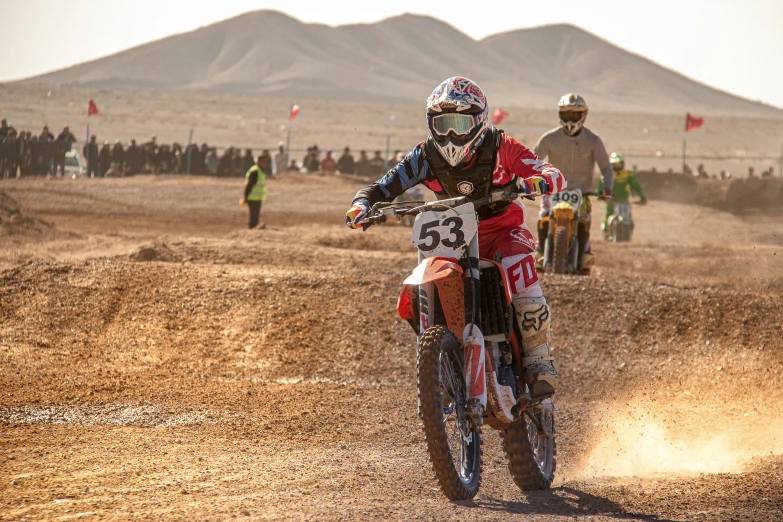 man riding on dirt bike on dirt course near mountains