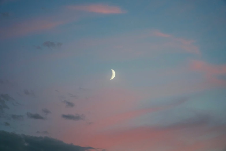 a white crescent in a blue sky with a crescent moon behind it