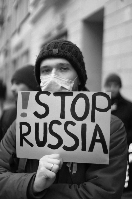 a protester holds up a sign that says stop russian