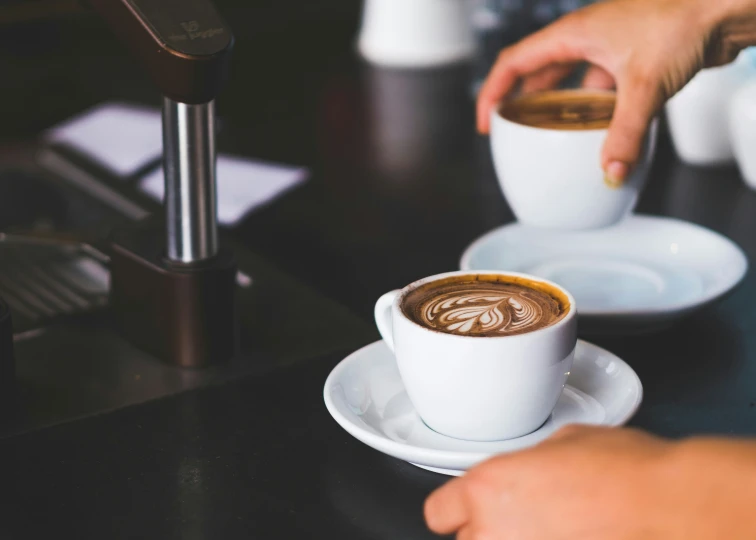 person's hand taking a chocolate latte off a coffee cup