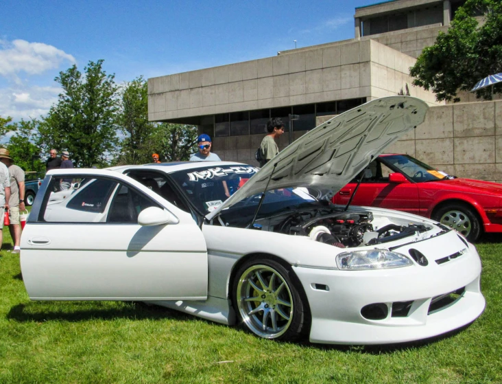 some cars are parked on some grass and the hood is open