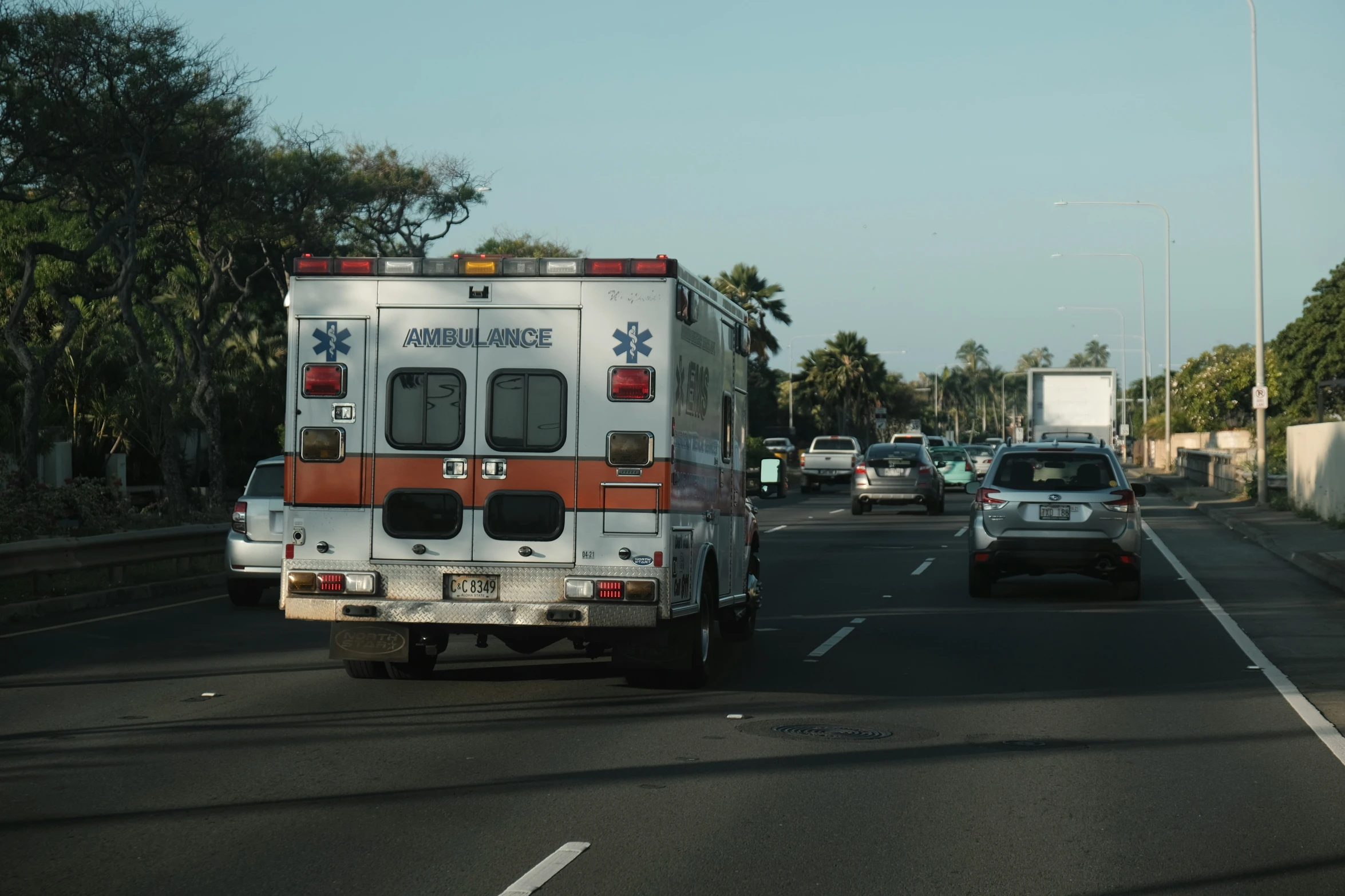 an ambulance is driving down the street while some cars pass