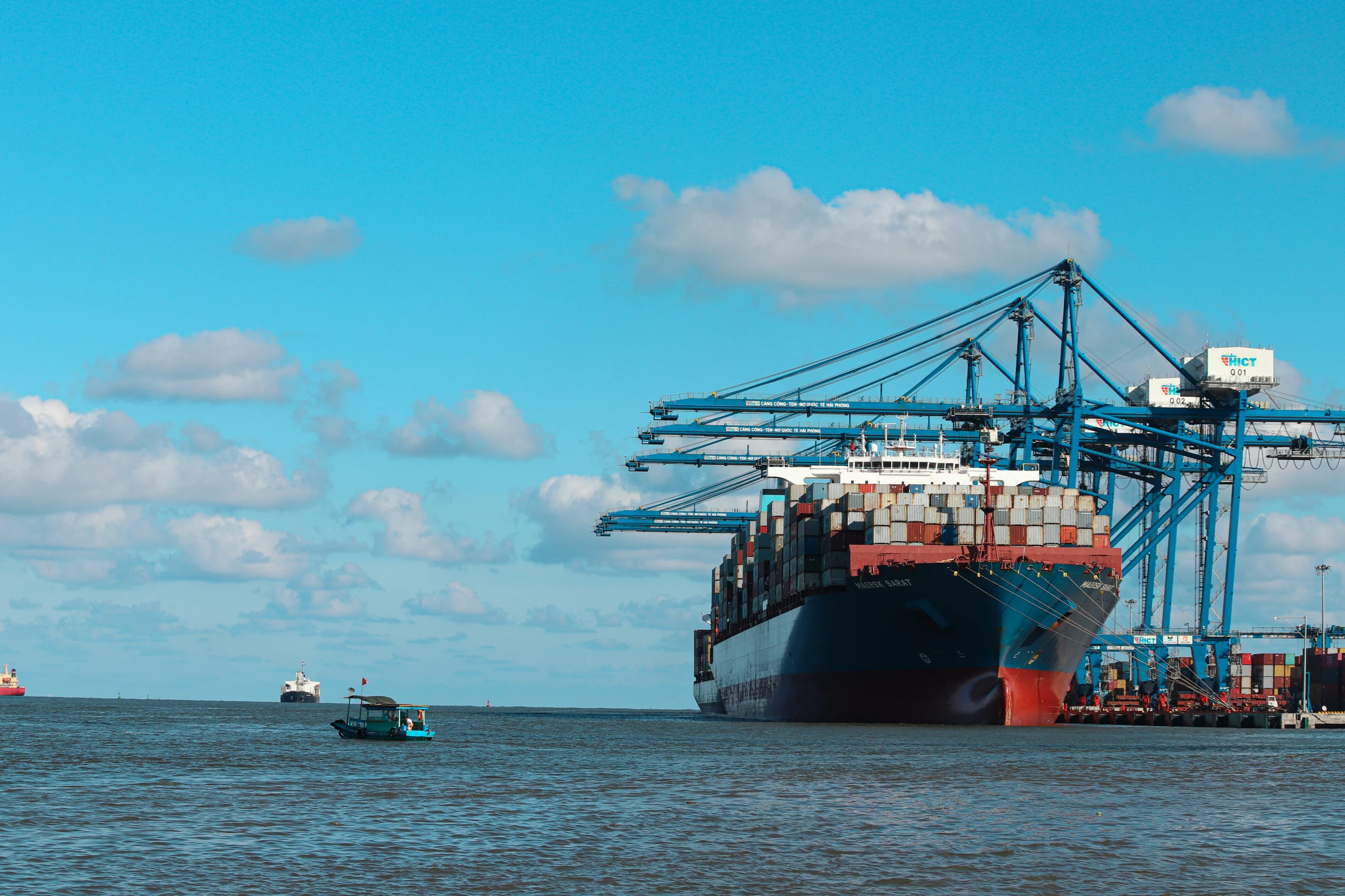 some boats in the water and a large ship with containers