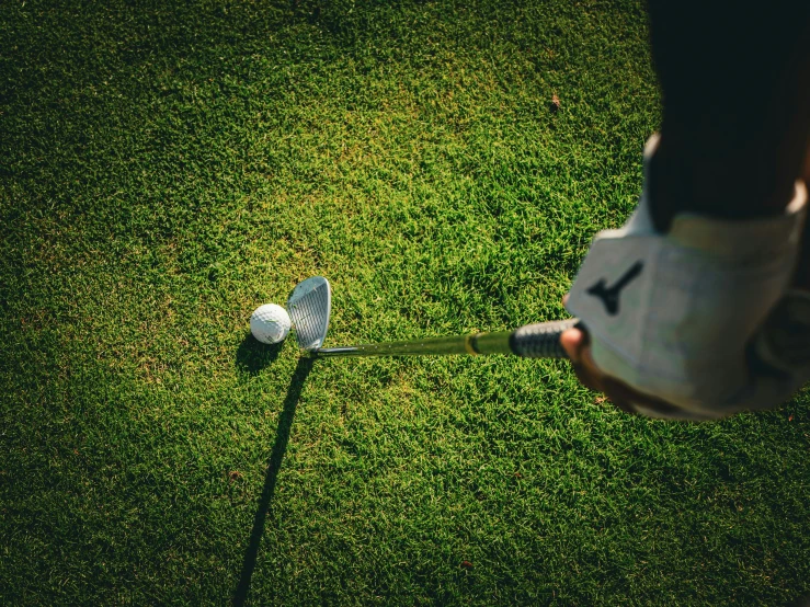 a person putting a golf ball on top of a tee