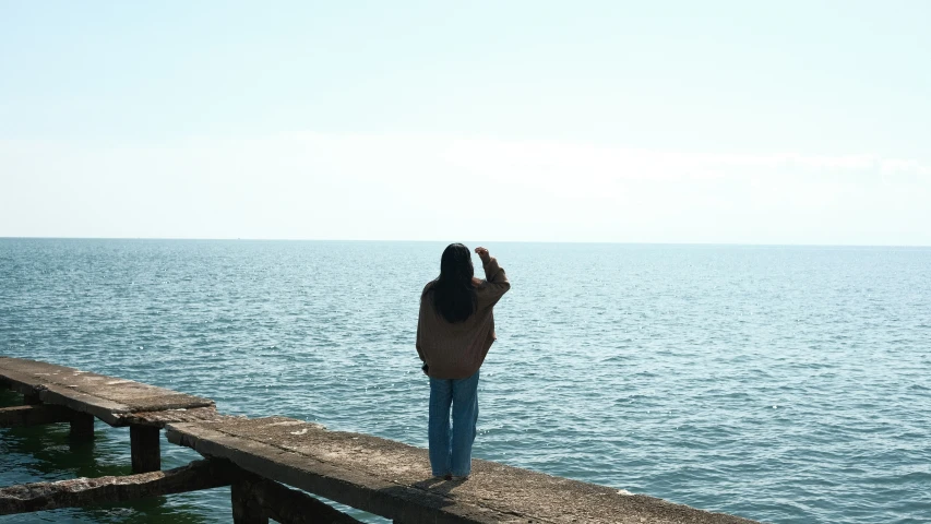 a woman standing on top of a wooden pier