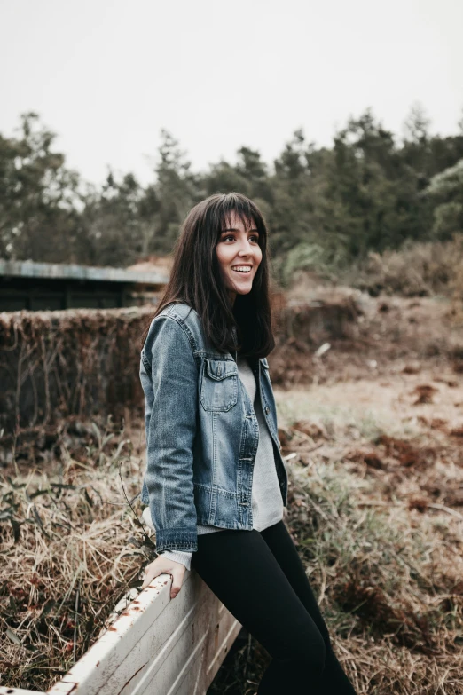 a woman is smiling for the camera as she leans on the fence