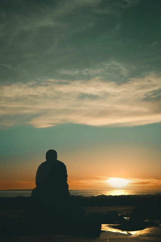 two people sitting on the sand near the water