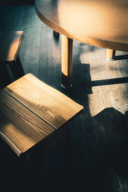 the light is shining on two wooden chairs next to a round dining table