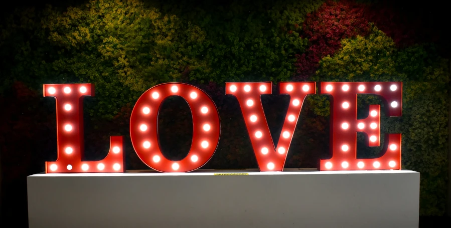 a large love light up sign in front of a tree