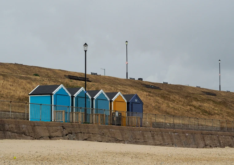 a bunch of little beach huts that are by the water