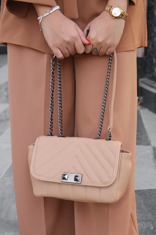 the person is holding a beige purse