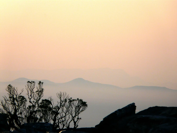 the silhouette of mountains and trees at dusk