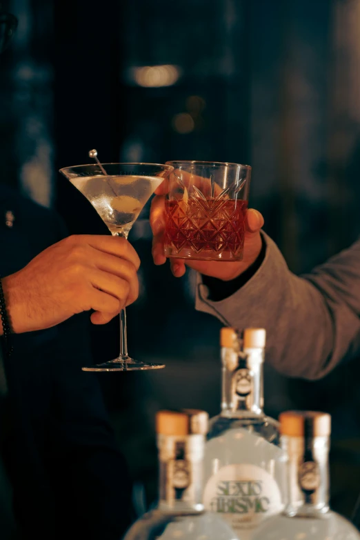 two men holding martini glasses that are half full
