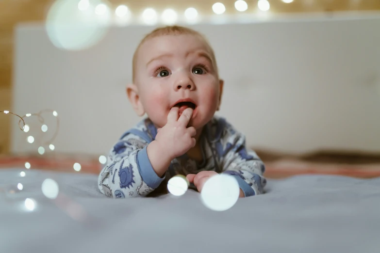 a baby chewing on some frosting on the bed