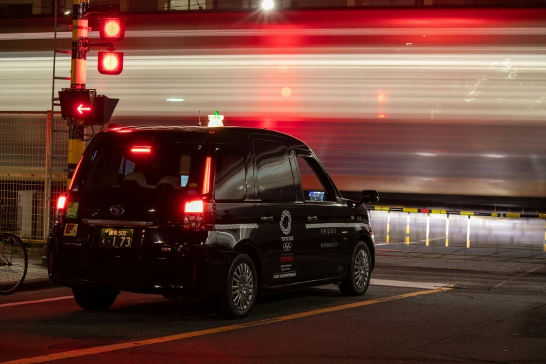 an automobile waits at a red light while a train passes by