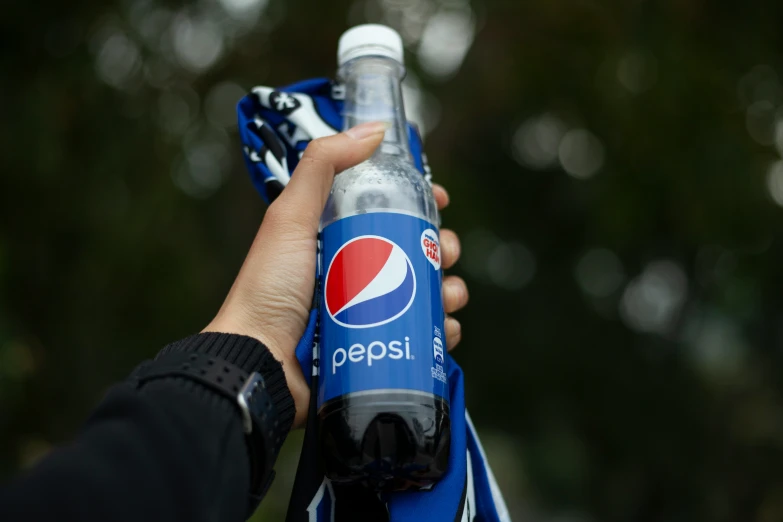 someone holds a pepsi bottle in the palm of their hand