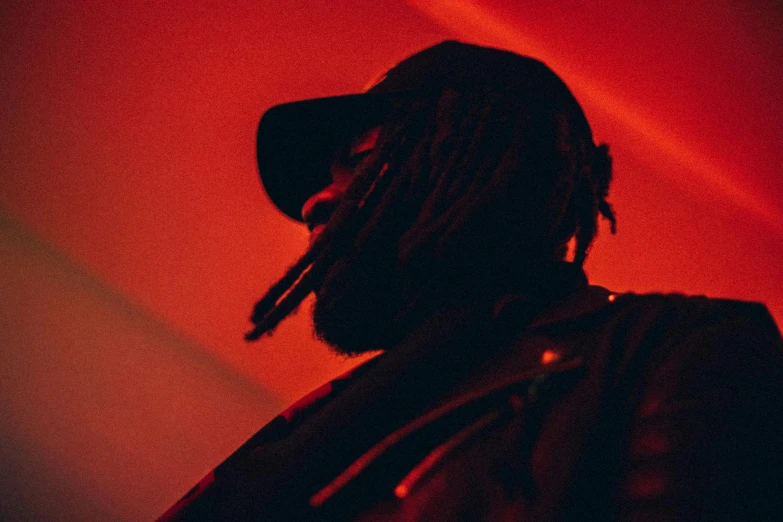 a man standing under a light with dreadlocks