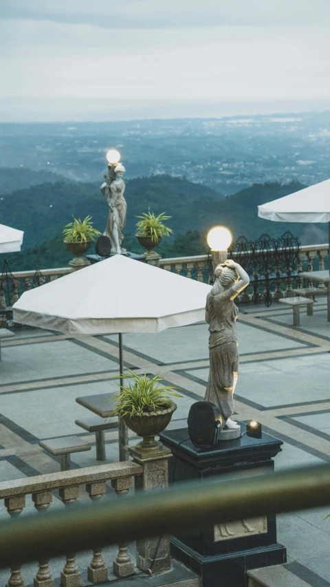 statues are placed near large open umbrellas at the top of a building