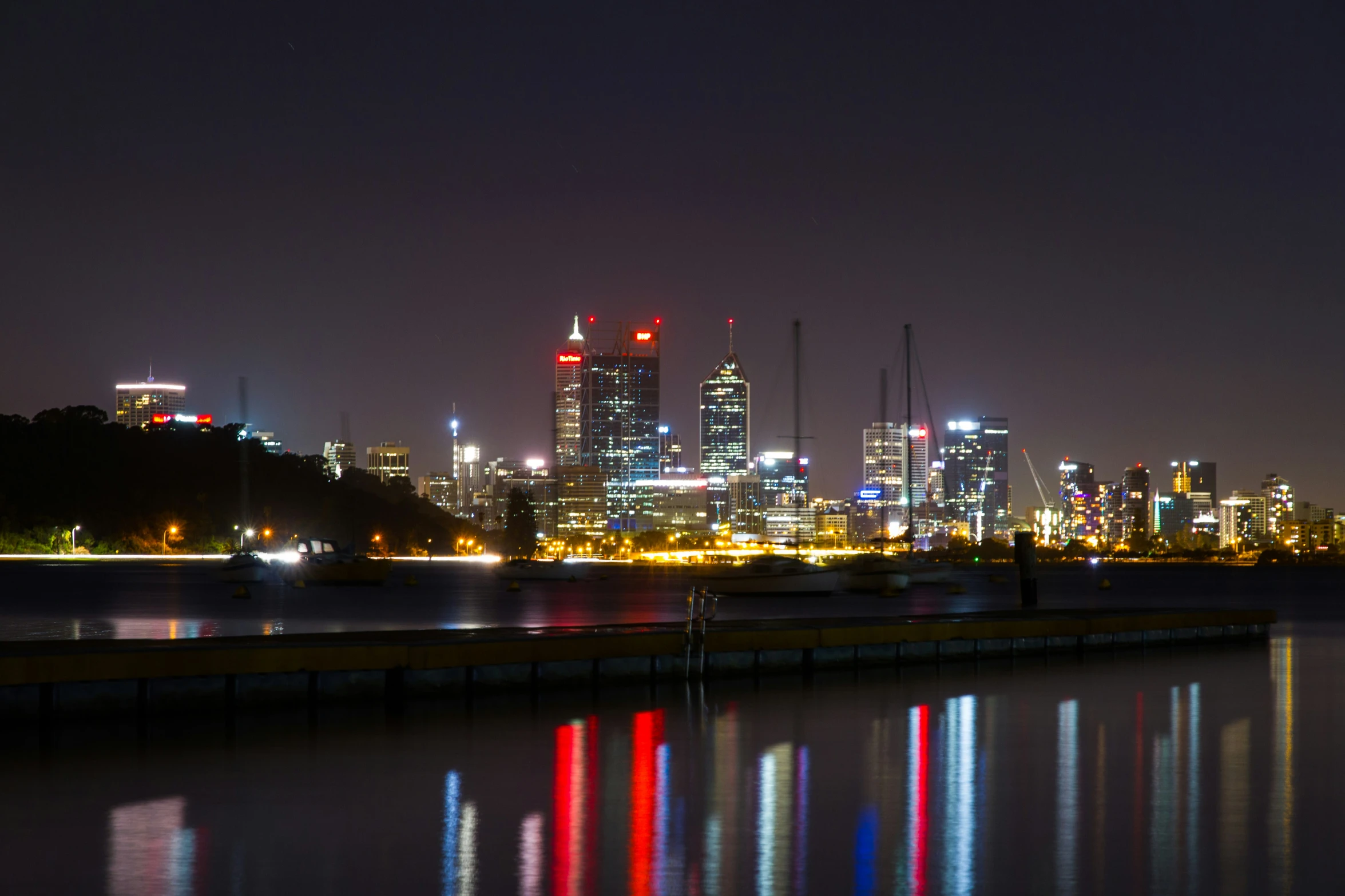 a body of water with boats on it near some tall buildings