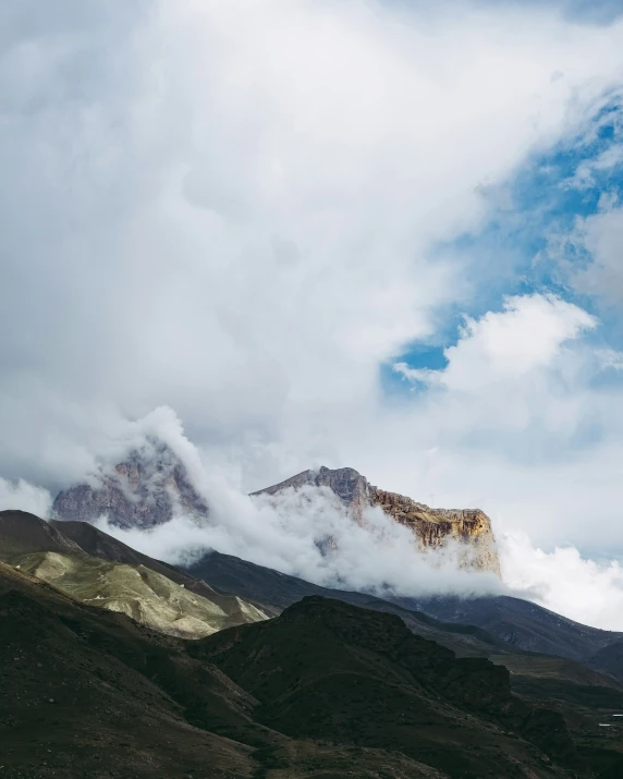 the tops of mountain covered in clouds on a cloudy day