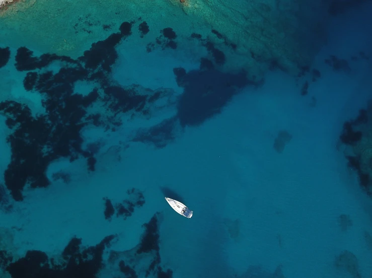 an aerial view of the ocean with white boats