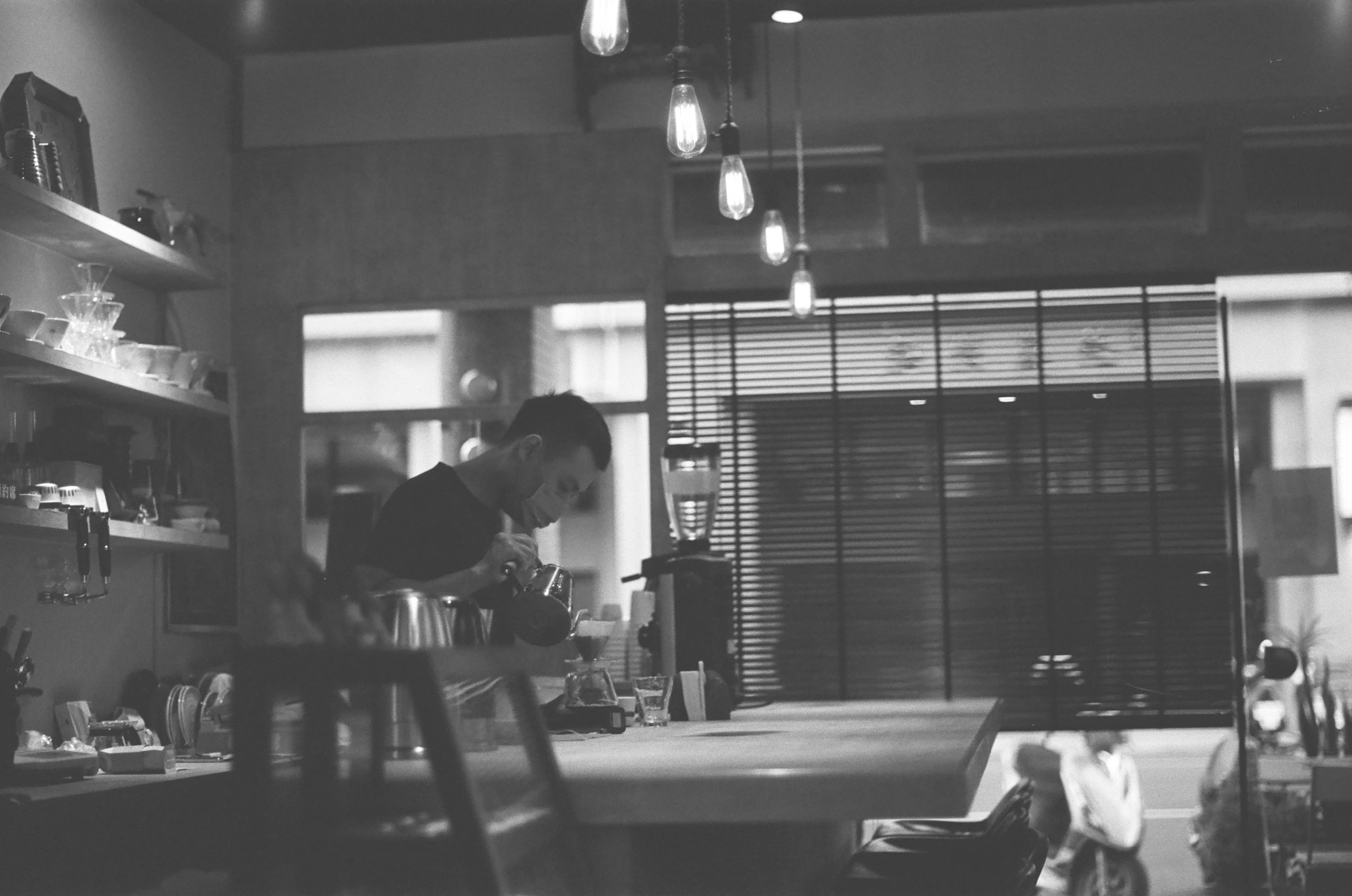 two people sit inside of a kitchen while a man works on a laptop computer