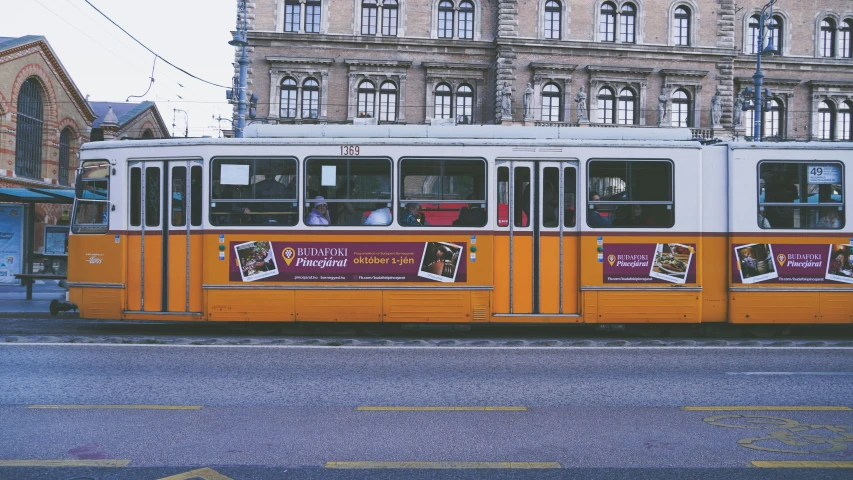 an orange trolley traveling past a tall building