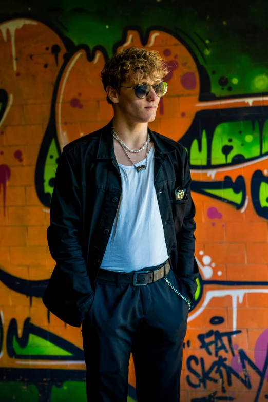 a young man in front of a graffiti covered wall