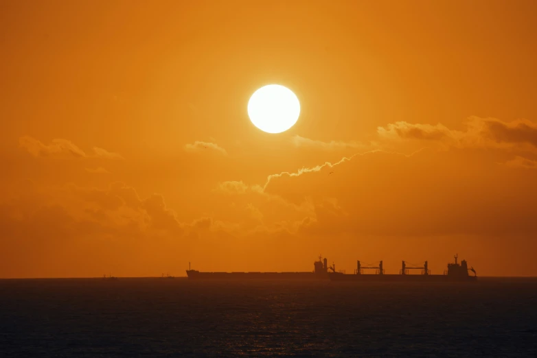 a huge ship sailing away from the sunset