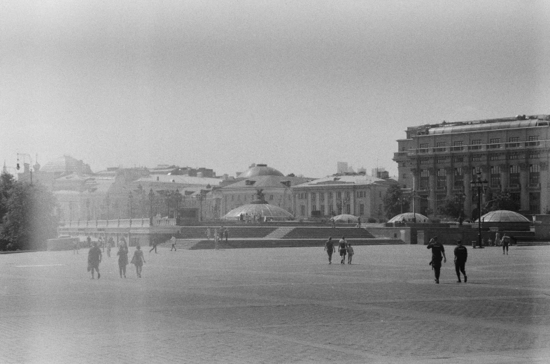 people walking in an empty area near a water fountain