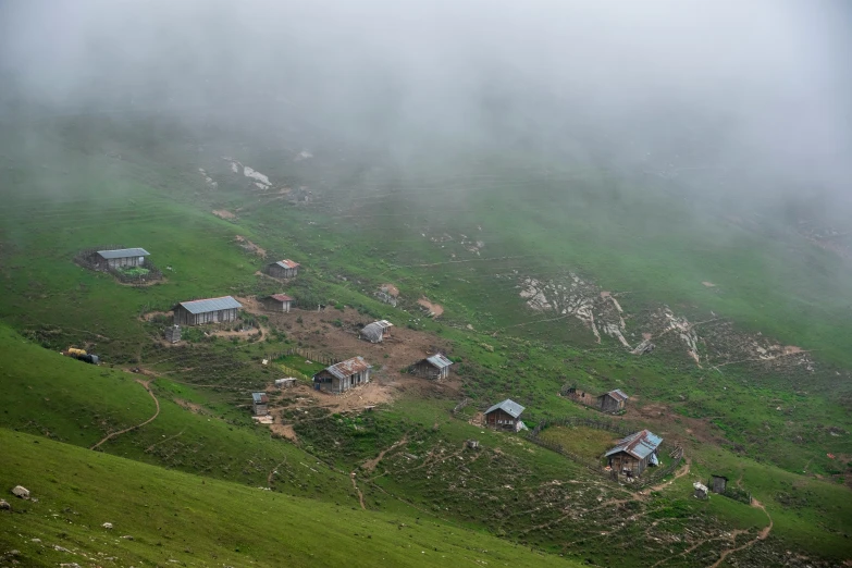 some houses are perched in the green hills