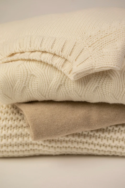 three white knit blankets folded and stacked on top of each other