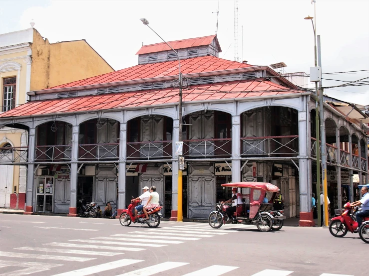 men riding bikes down the street past buildings