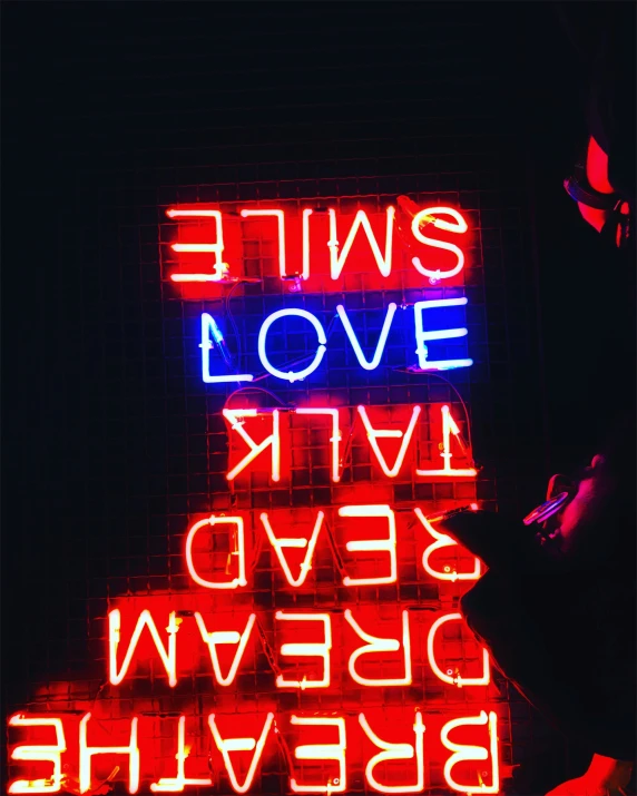 neon sign with an evil face and four words below it