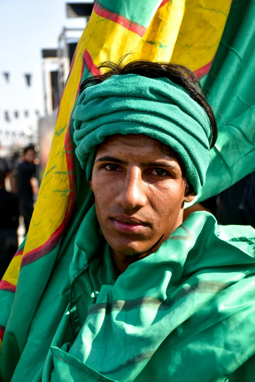 a man wearing a green head wrap and scarf